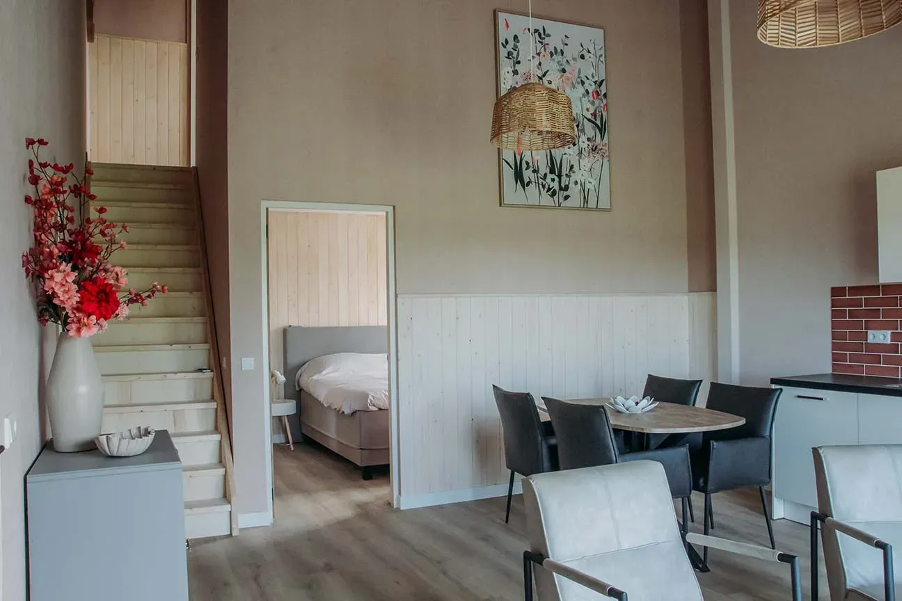 Lichte woonkamer met trap en eettafel in B&B 't Bloemenveld